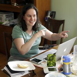 In this Wednesday, June 27, 2018, photo, Kate Sharaf, who is spearheading a small group of stay-at-home mothers to organize an immigration rally, gestures to other volunteers while working at home in Portland, Ore. The small group of mothers organizing Saturday's rally in Portland to coincide with Families Belong Together rallies nationwide, are working almost around-the-clock to pull together an event expected to attract 5,000 people. (AP Photo/Don Ryan)