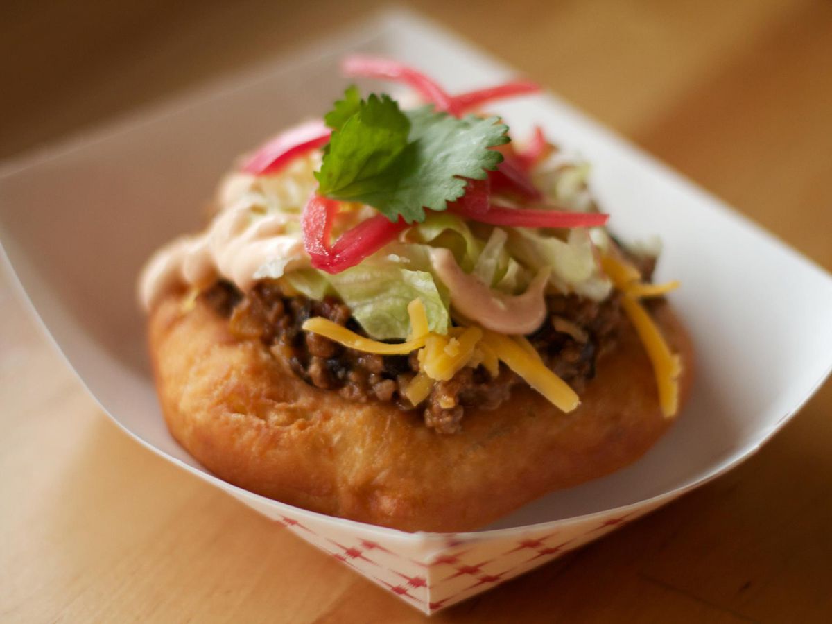 A fry bread taco topped with meat, cilantro, and pickled onions from Off the Rez Cafe
