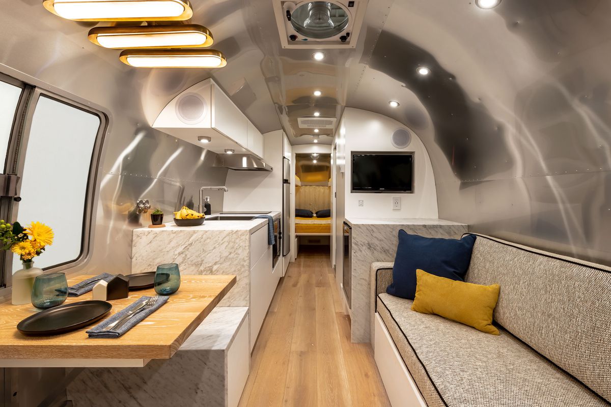 The interior of a shiny aluminum Airstream renovated in blues, whites, and grays. 