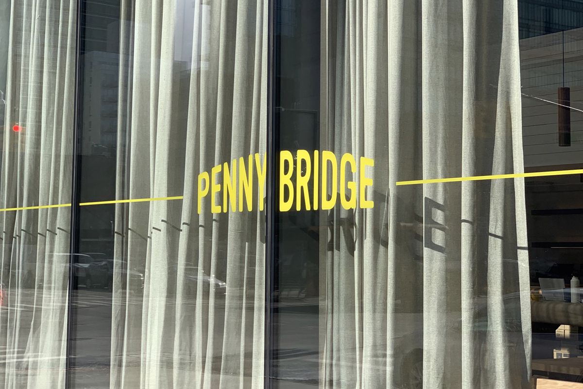 The words “Penny Bridge” are written in yellow font on a glass window