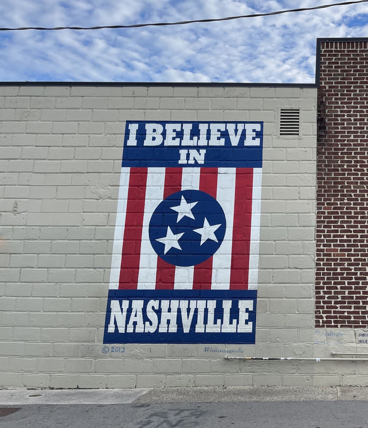 A mural with a flag reading “I Believe in Nashville”.