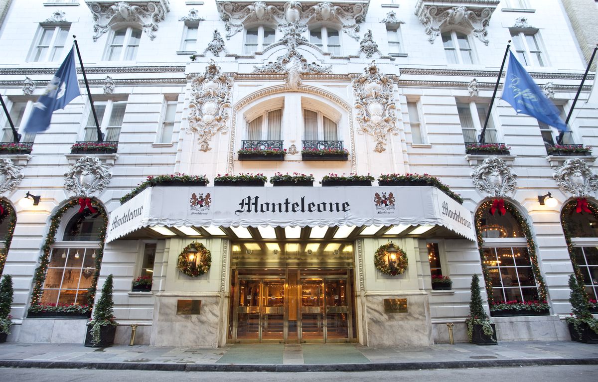 The exterior of the Hotel Monteleone in New Orleans. The facade is white with an awning over the entrance that says: Monteleone. There are arched windows and elaborate white decorative detail next to the windows.