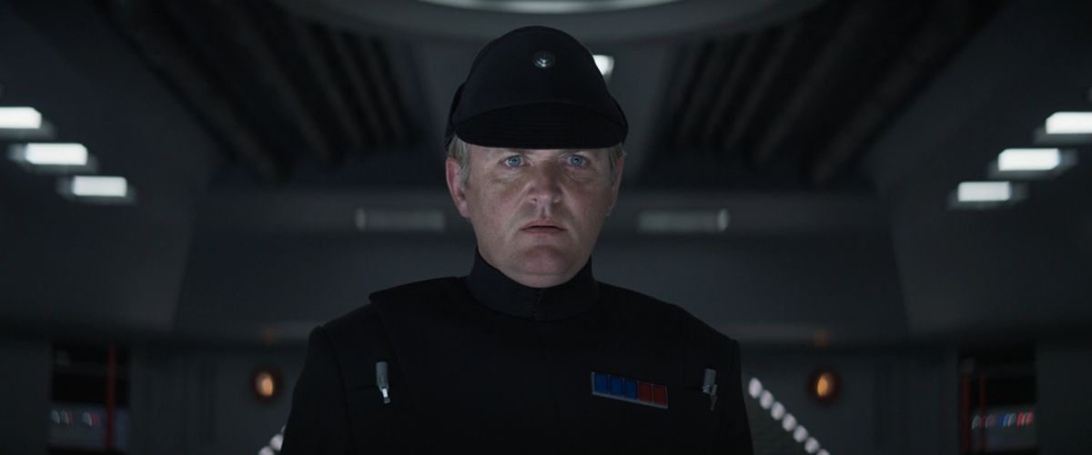 Um oficial imperial uniformizado parece chocado e enojado em Andor.