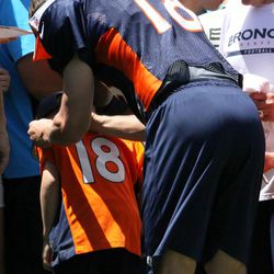 Broncos quarterback Peyton Manning signs a young fans jersey after practice