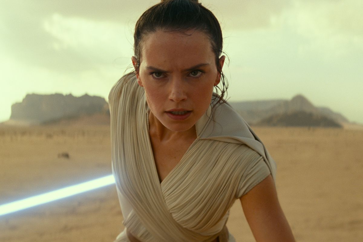 Daisy Ridley as Rey, holding a lightsaber in the desert