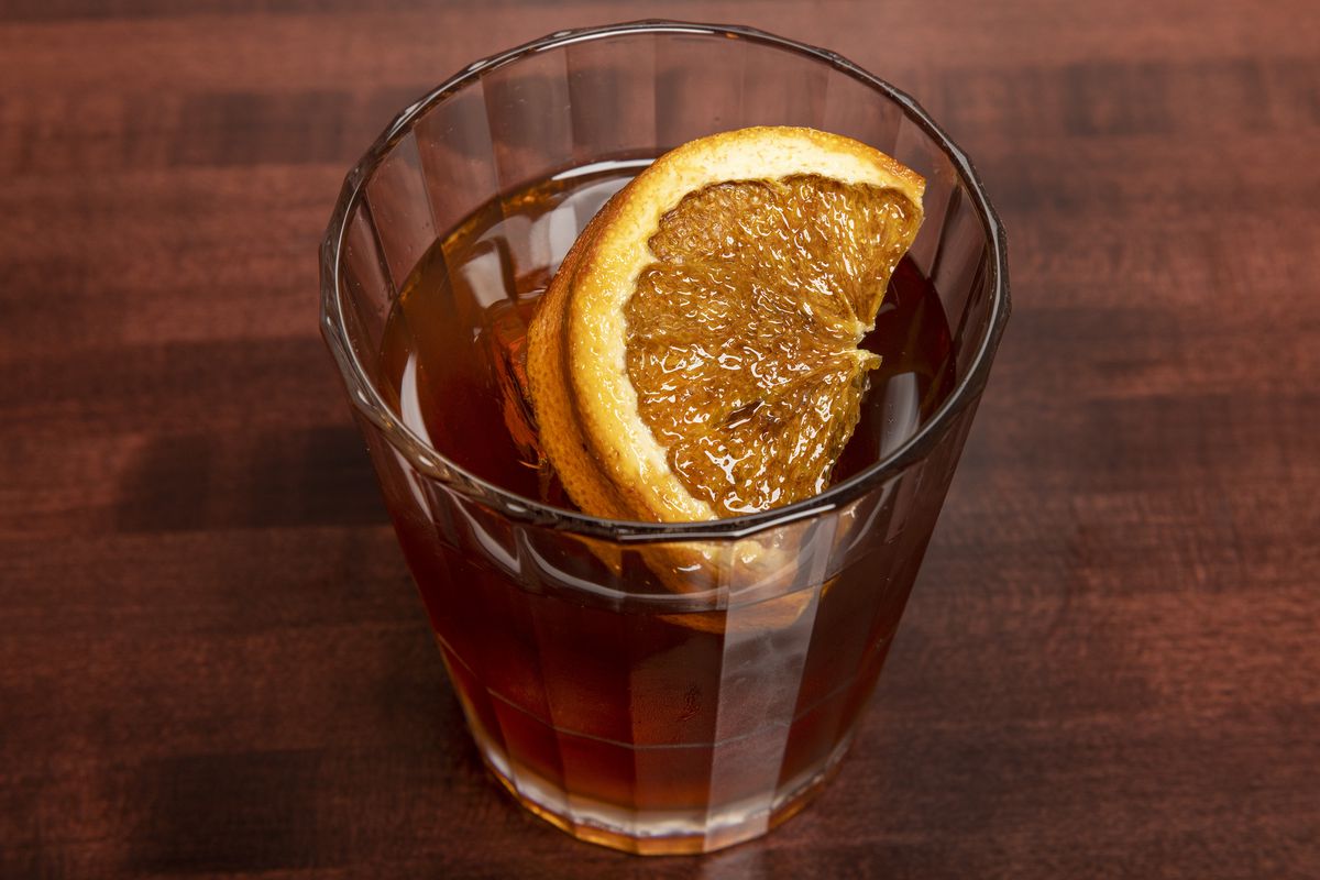 A whiskey cocktail with a slice of orange.