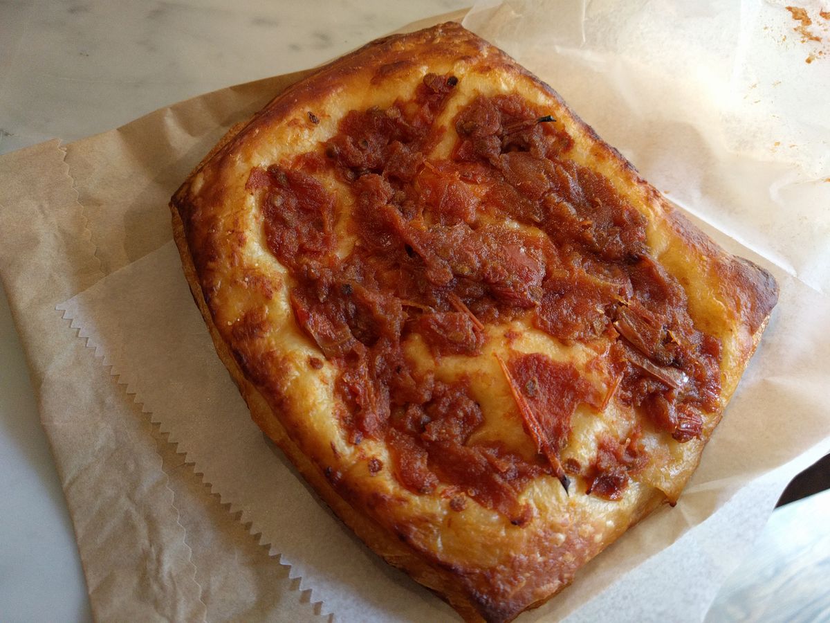 A squarish flaky pastry with red sauce in the middle.