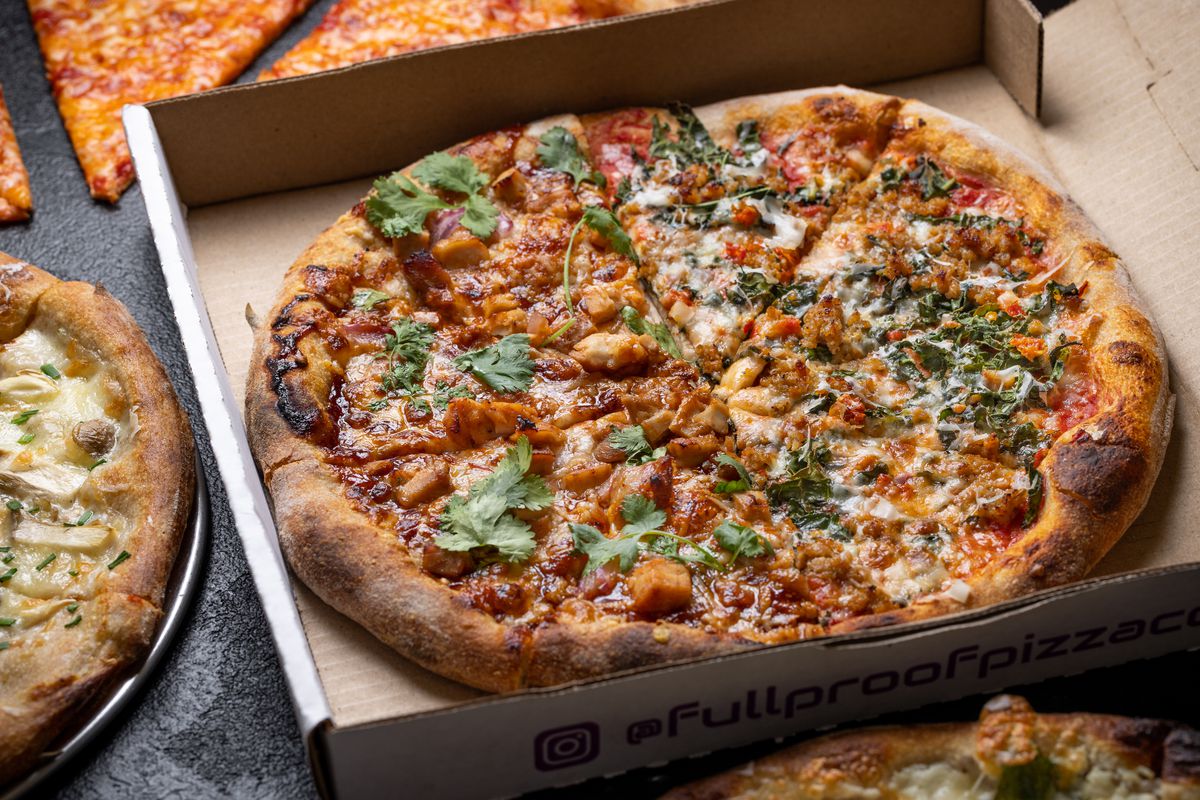 A pizza topped with barbecue chicken, tomato sauce, cheese, and cilantro in a to-go pizza box.