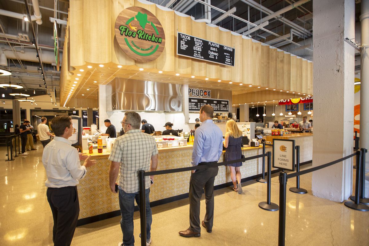 A food hall stall with four people standing in line.