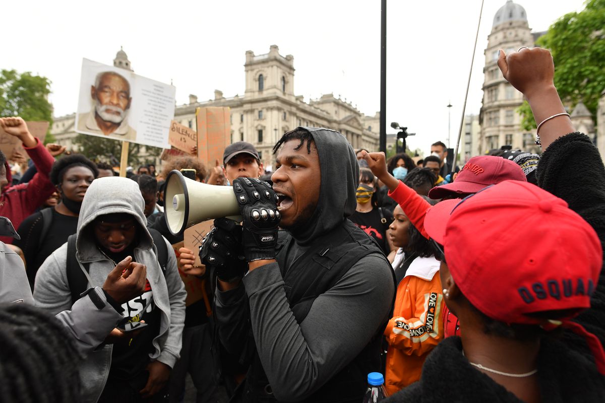 John Boyega speaks through a megaphone to a large crowd of protesters