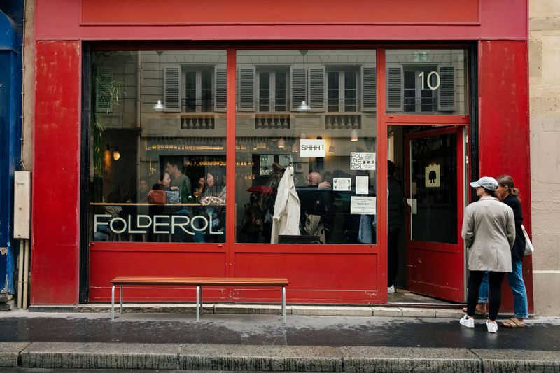 The outside facade of a restaurant that is painted red with text on a window that says Folderol and the number 10 above a door.