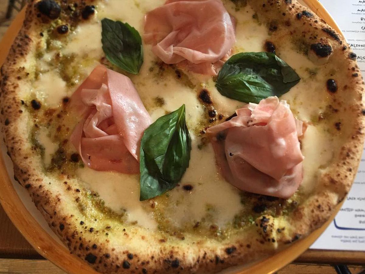 Mortadella, basil, and cheese on a pizza seen from a birdseye view, at Pizzeria Pellone