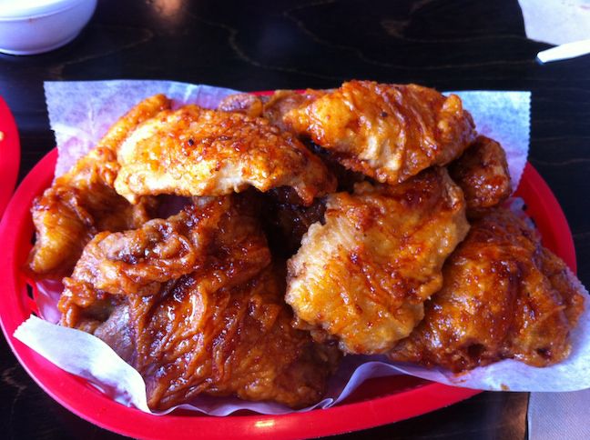 A pile of Korean fried chicken in a red plastic basket lined with wax paper.