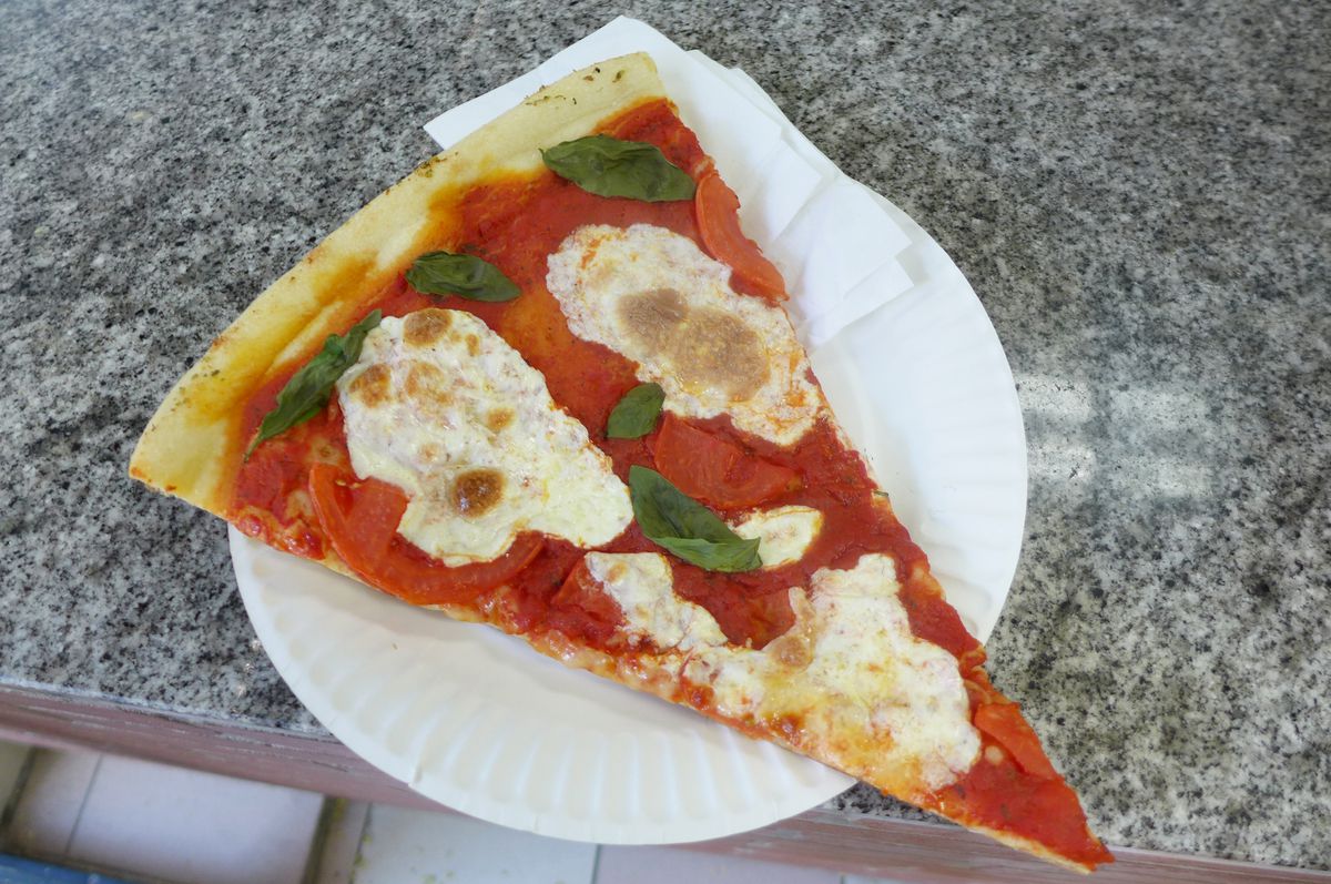 A wedge of pizza with fresh mozzarella on it.