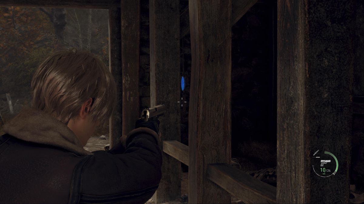 Leon S Kennedy aims at a blue medallion inside the large barn of the Farm area in Resident Evil 4 remake
