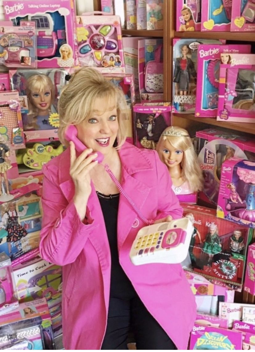Barbie voice Chris Lansdowne surrounded by Barbie products.