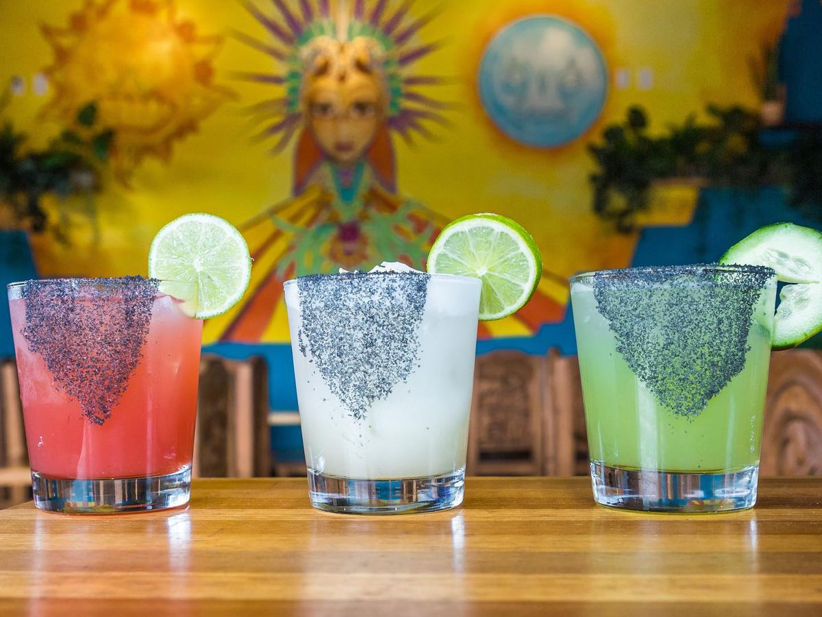 Three colorful cocktails with mural in background.