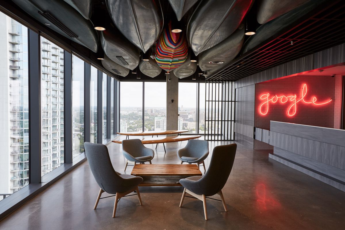 room in high-rise with window walls and canoes on the ceiling and a neon sign that says “google” in script