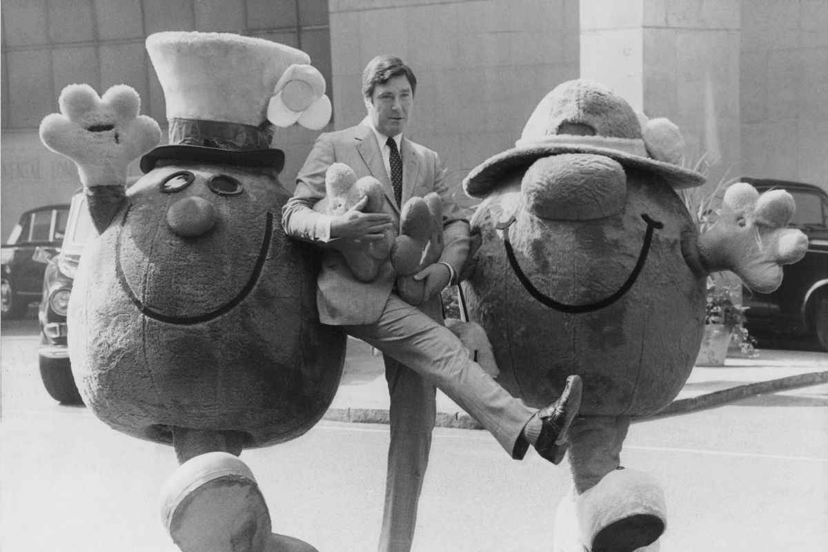 A black and white photo of Roger Hargreaves with Mr. Men characters in mascot costumes