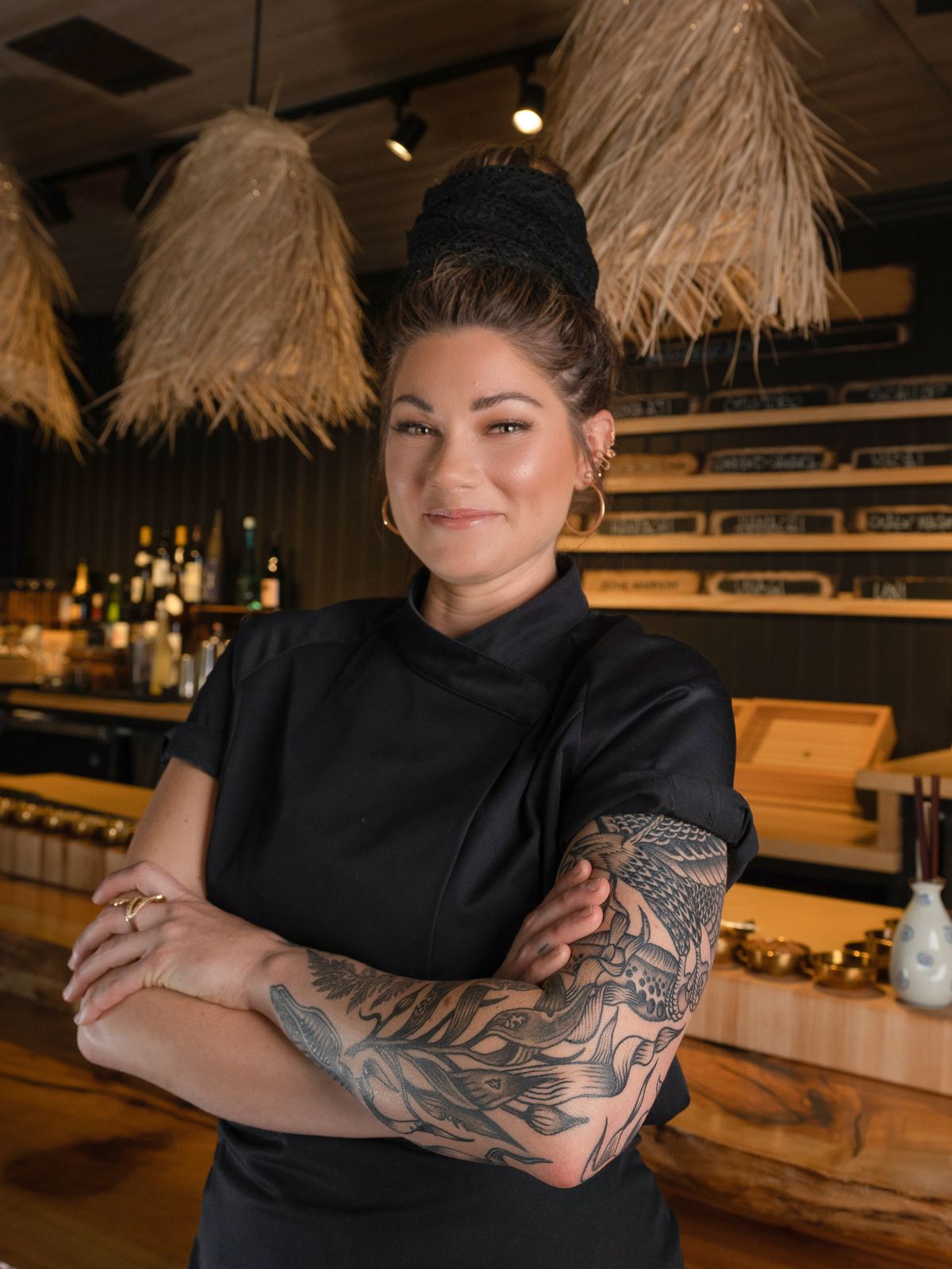 A chef with black apron in front of a bar.