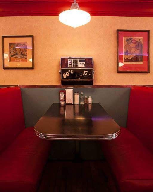 A retro diner booth with a small jukebox on the wall.