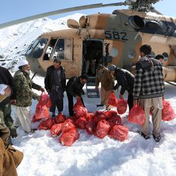 Afghans carry emergency food to a helicopter to deliver to avalanche survivors in Panjshir province, north of Kabul, Afghanistan, Friday, Feb. 27, 2015. The death toll from severe weather that caused avalanches and flooding across much of Afghanistan has jumped to more than 200 people, and the number is expected to climb with cold weather and difficult conditions hampering rescue efforts, relief workers and U.N. officials said Friday. 