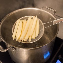 The fries are initially blanched in salt water for 14 minutes, and then they are cooled.