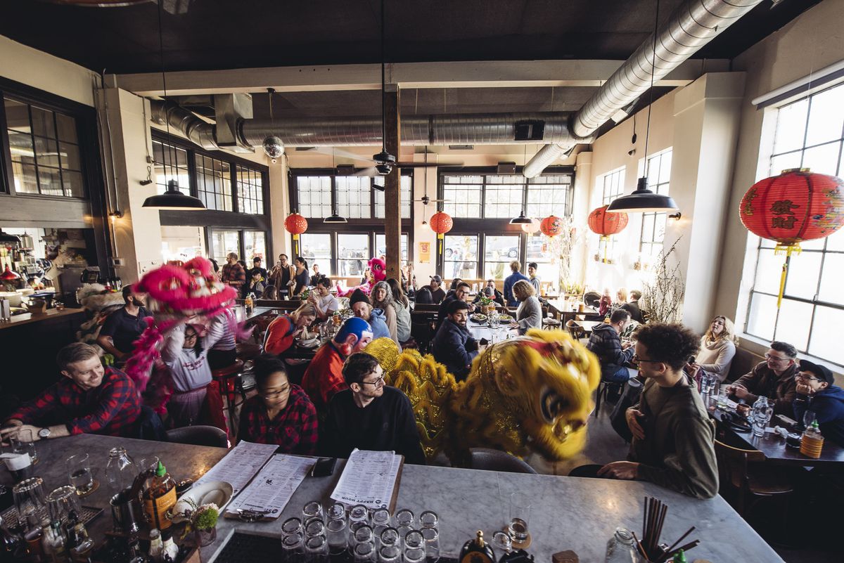 A dining room full of people, with a Chinese lion dance making its way between tables.