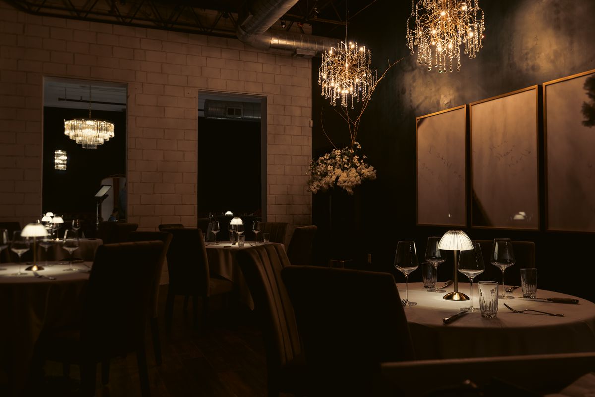 Patton’s dark and moody dining area, illuminated by small lamps and chandeliers.