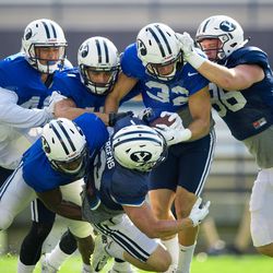BYU wide receiver Garrett Juergens, center, is tackled by several defenders — including Akile Davis, lower left, Morgan Unga, upper far left, Sam Baldwin, third from left, and Gavin Fowler (32) — while tight end Hunter Marshall (96) blocks on the play during the team's scrimmage at LaVell Edwards Stadium on Thursday, Aug. 18, 2016.