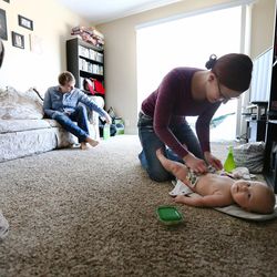 Kendle Webster changes a diaper on her daughter Emery, as she and husband Michael Webster talk about their lives, moving and jobs at their home in Cottonwood Heights as the Census Bureau reports that Utah is the nation's fastest growing state on Tuesday, Dec. 20, 2016.
