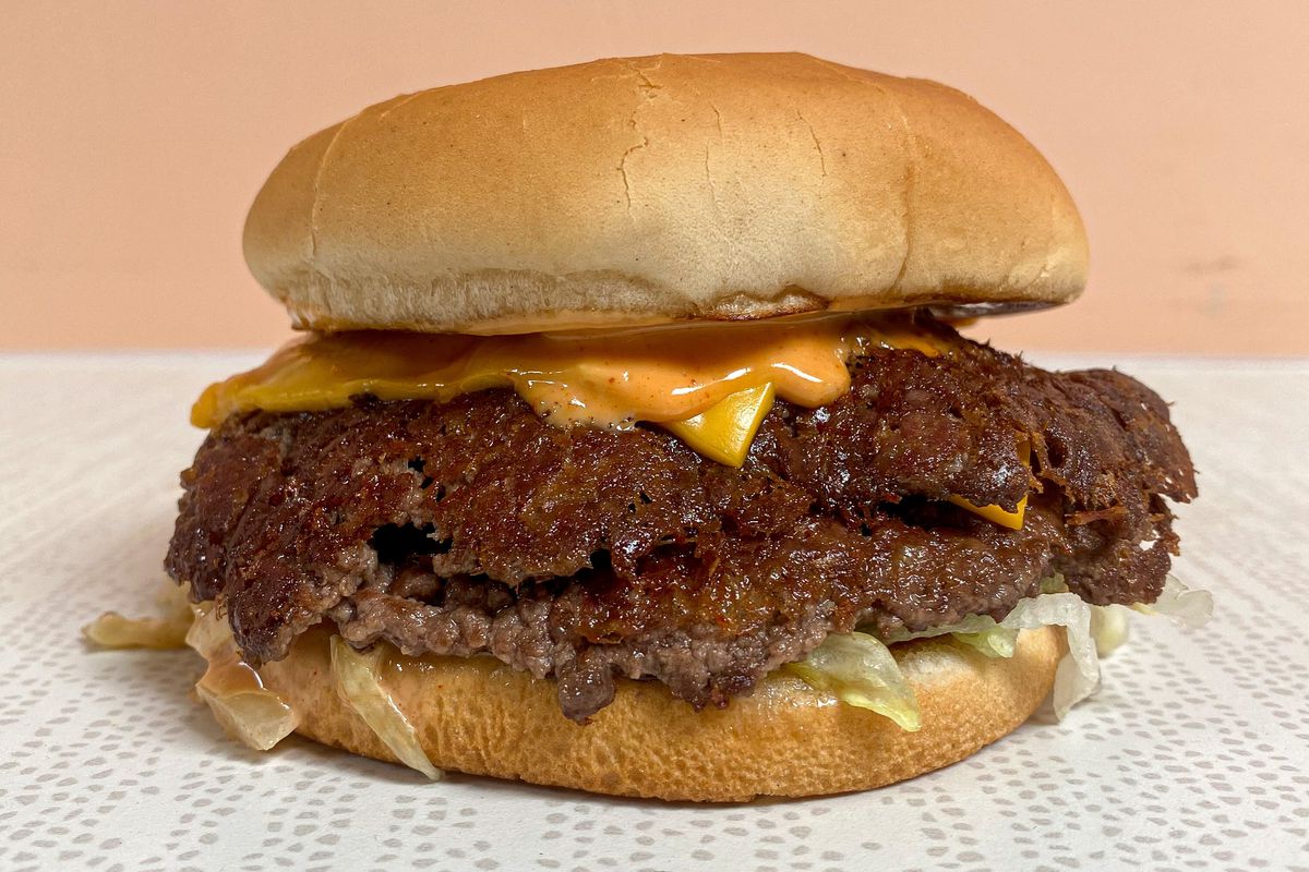 A smashed burger on white linoleum, shown from the side