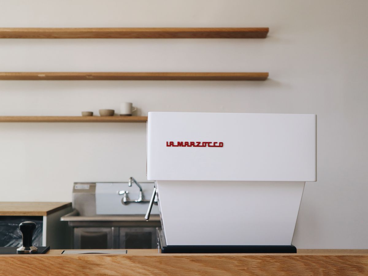 A white coffee machine with red text that says la marzocco.
