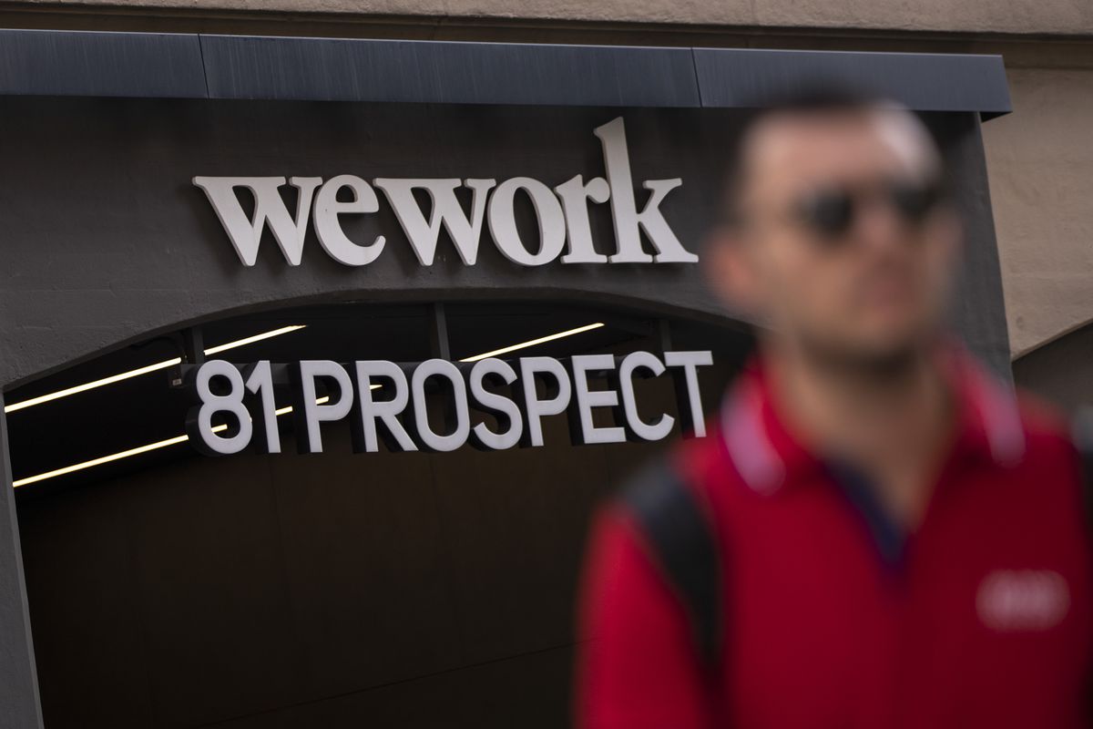 Man whose face is out of focus walks away from a WeWork location at 81 Prospect in New York City.