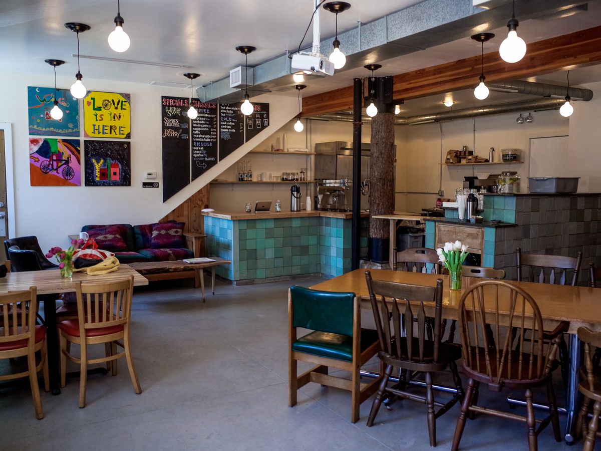 A cozy coffee shop interior with wooden tables and colorful art on the walls. 