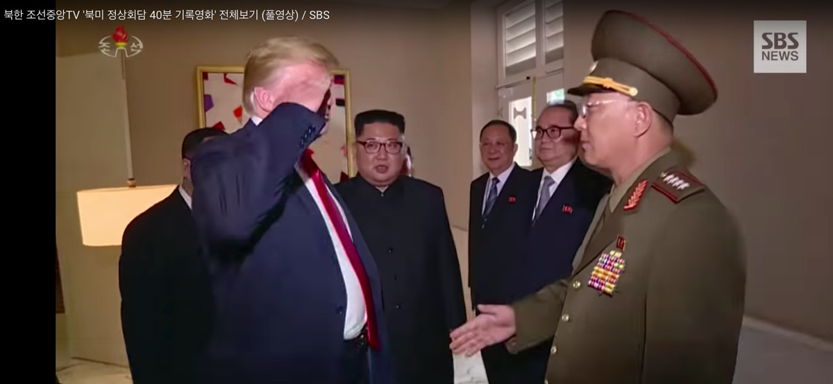 President Donald Trump salutes a senior North Korean general as Kim Jong Un looks on.