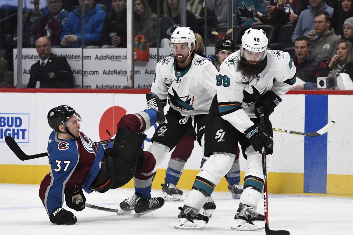 DENVER, CO - JANUARY 02: Colorado Avalanche left wing J.T. Compher (37) hits the ice after a hit by San Jose Sharks defenseman Brenden Dillon (4) in the third period at the Pepsi Center January 02, 2019. San Jose Sharks defenseman Brent Burns (88) goes af