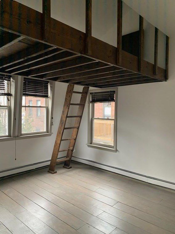 An empty room with a prominent loft reachable via ladder.