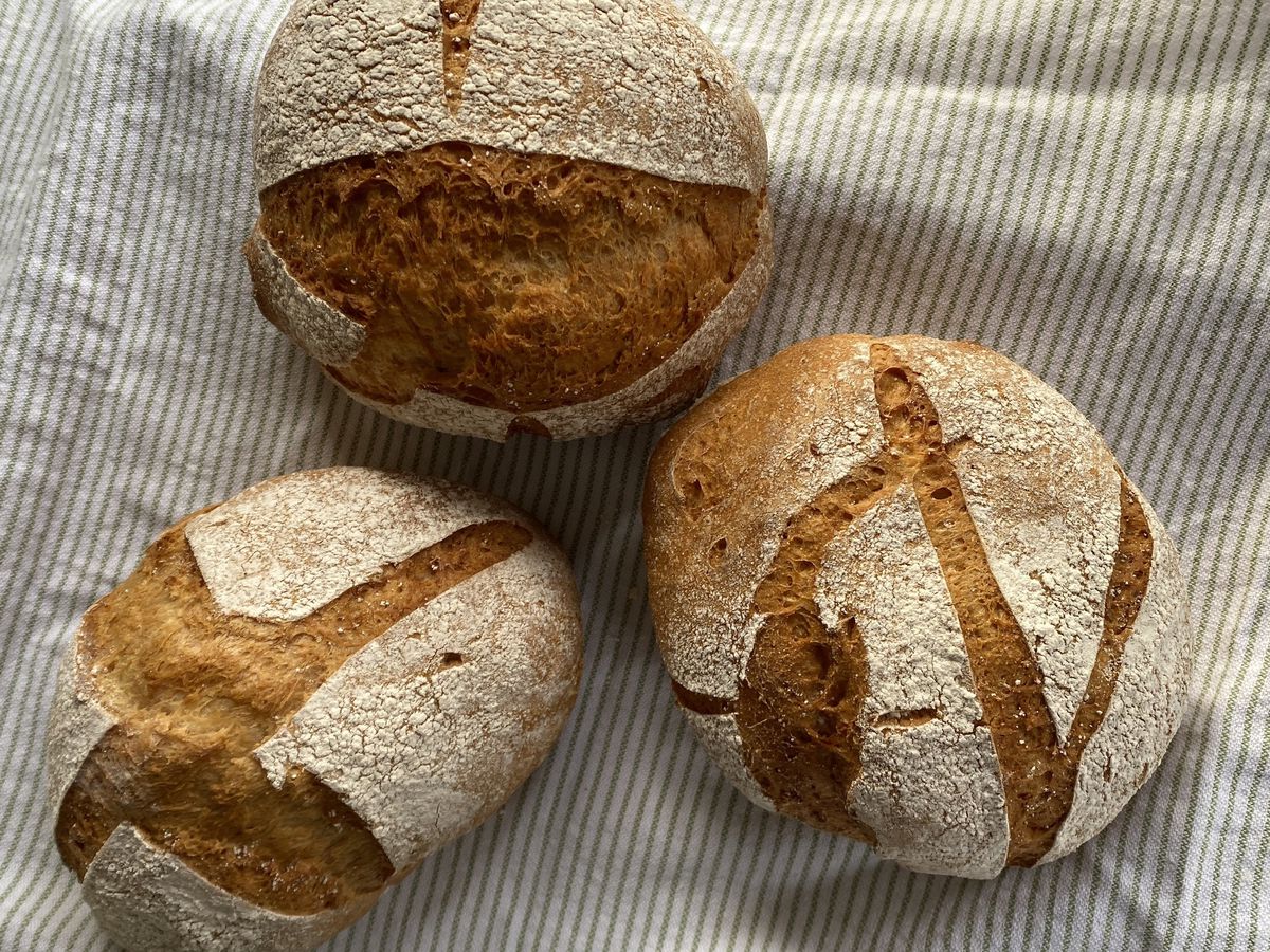 Three loaves of bread on a striped cloth. 