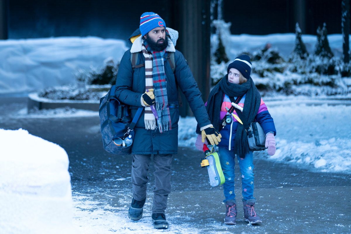 A man (Himesh Patel) and a little girl (Matilda Lawler) walk through a frozen landscape dressed in winter attire.
