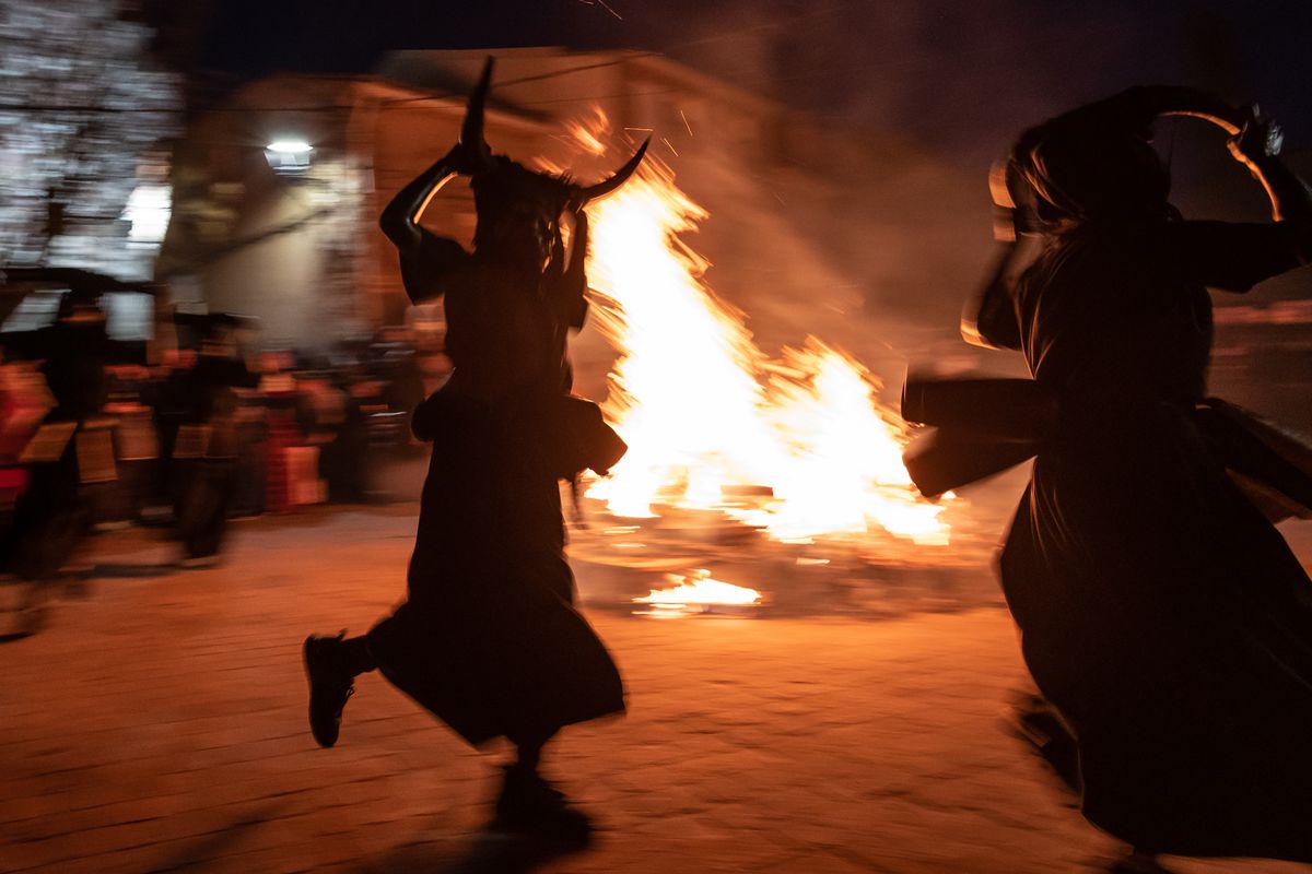 People dance by a bonfire with their faces, arms and hands...