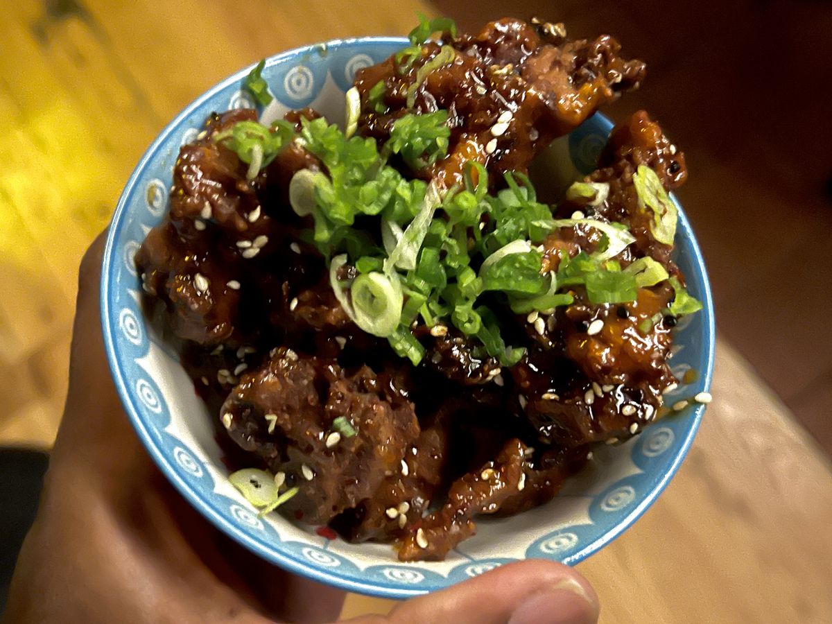 A bowl of fried chicken with green onions.