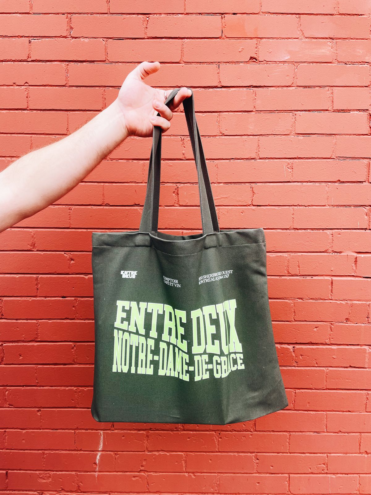 green tote against red brick wall