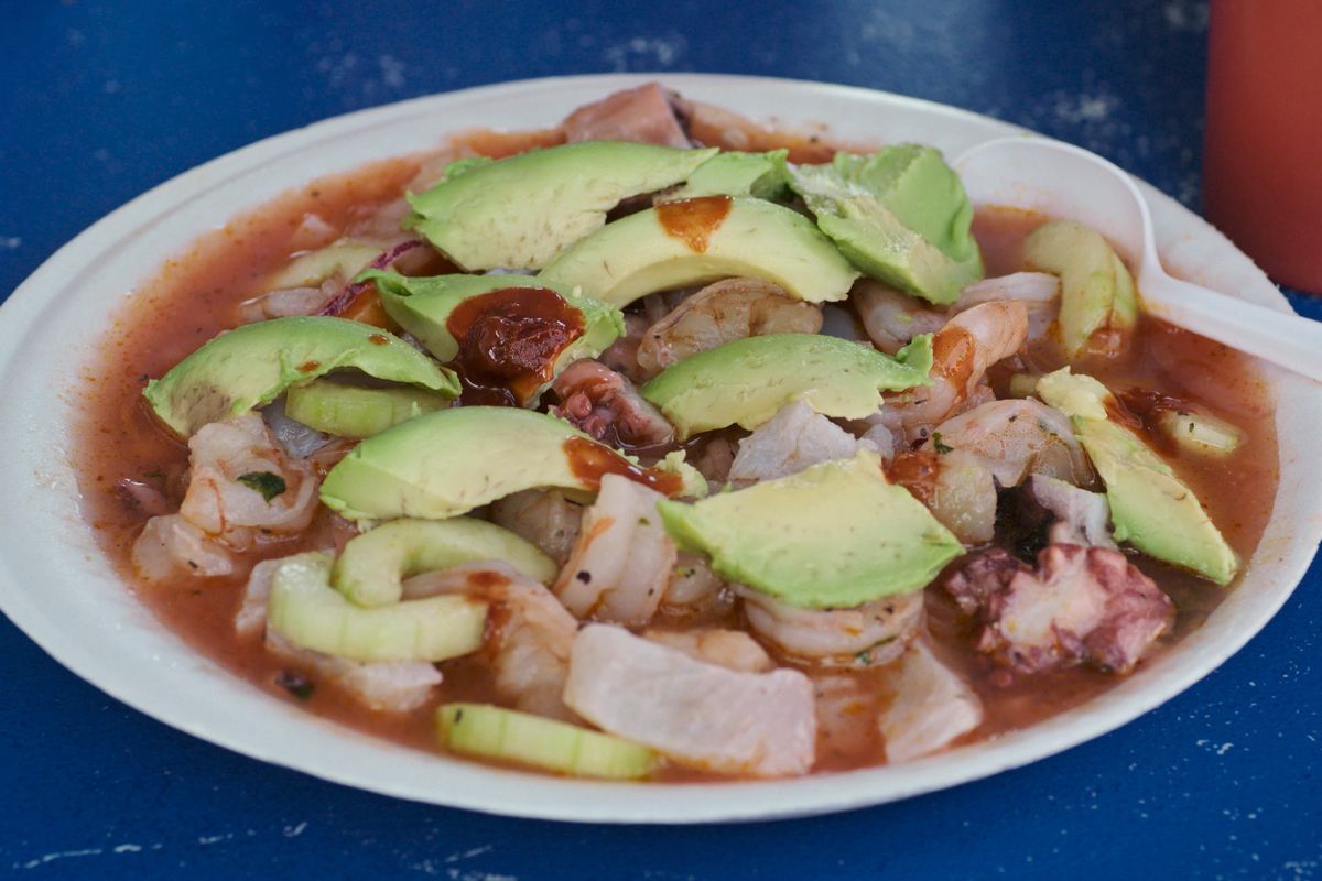 A plat of mariscos with avocado on top.