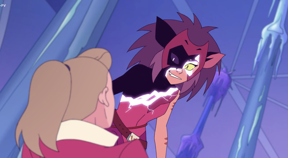 In a purple chamber, Catra looms over Adora. This version of Catra is distorted, half her body glitched and black. Her yellow eyes are frenzied, a maniacal smile on her face. Adora is on the floor, her hair in a ponytail. We do not see her face.