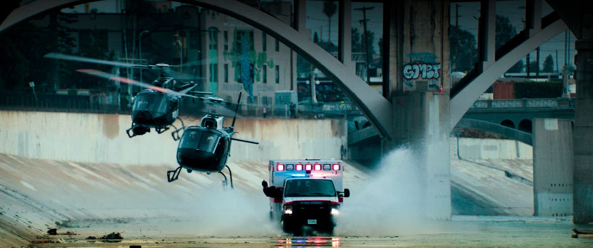 An ambulance is chased by two helicopters down the L.A. River