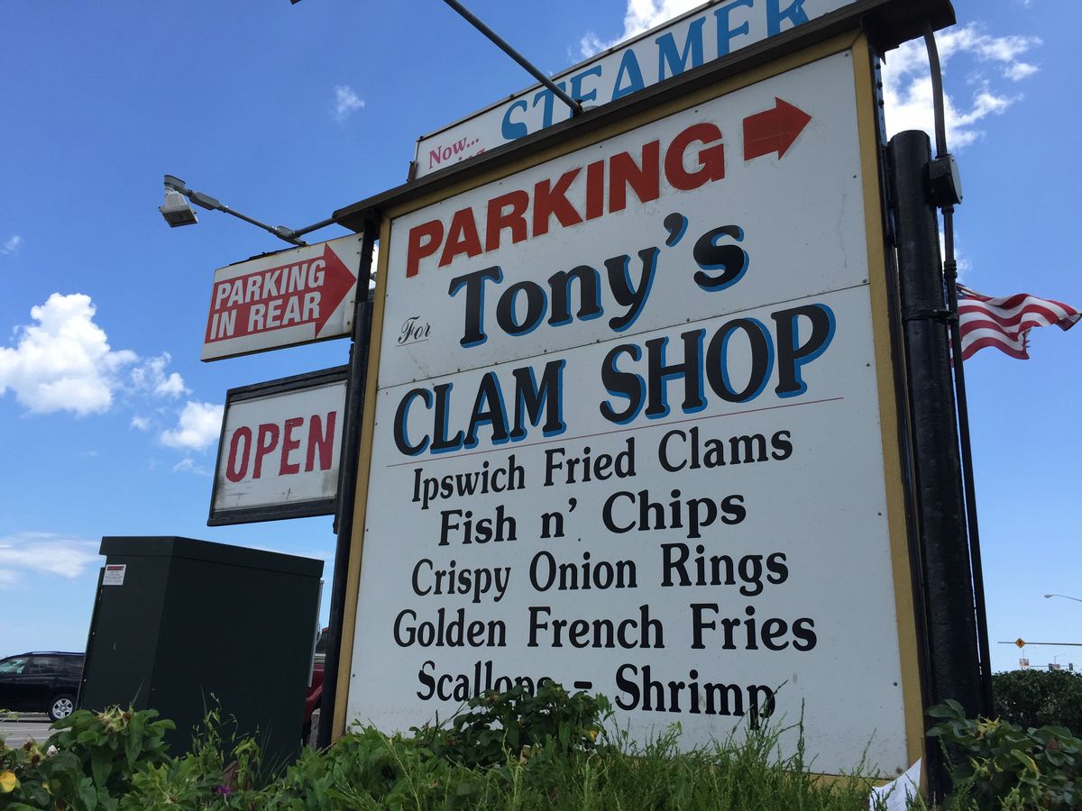 A giant white sign reads Tony’s Clam Shop and mentions a variety of foods, including Ipswich fried clams, scallops, and shrimp.