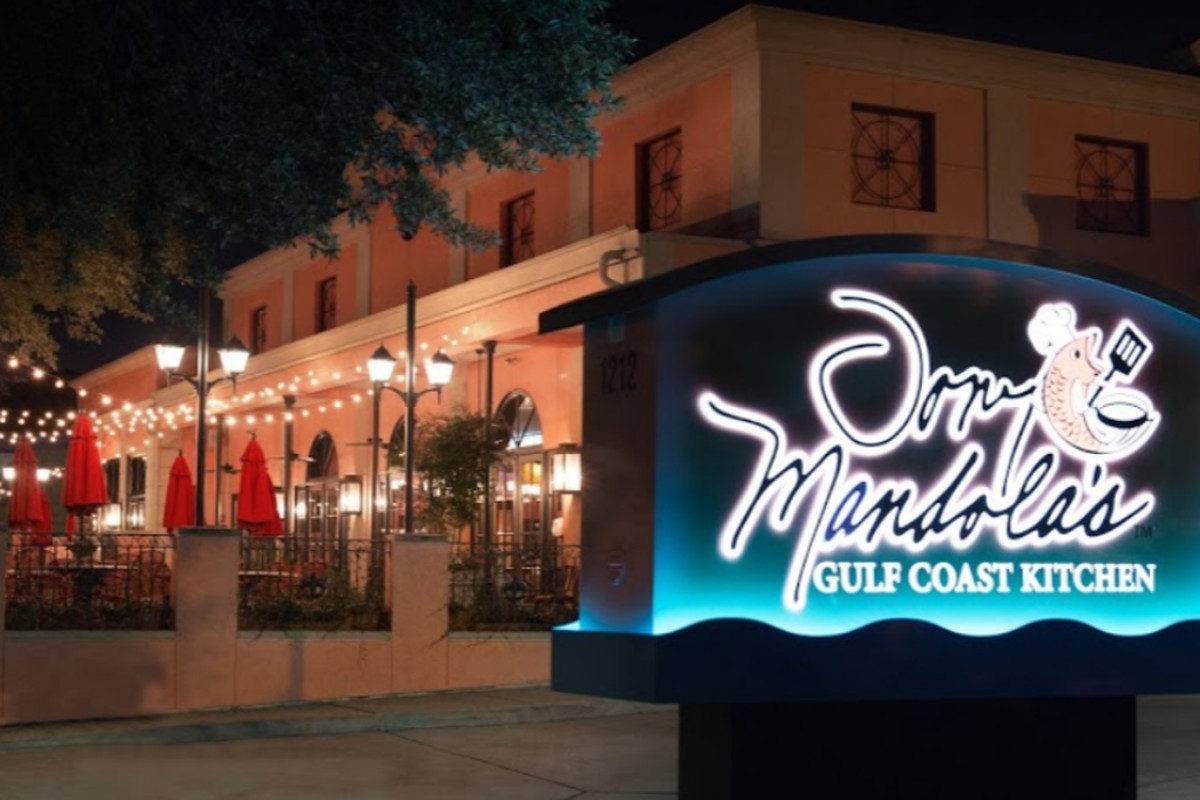 the front of a restaurant at night, with a neon sign reading Tony Mandola’s Gulf Coast Kitchen