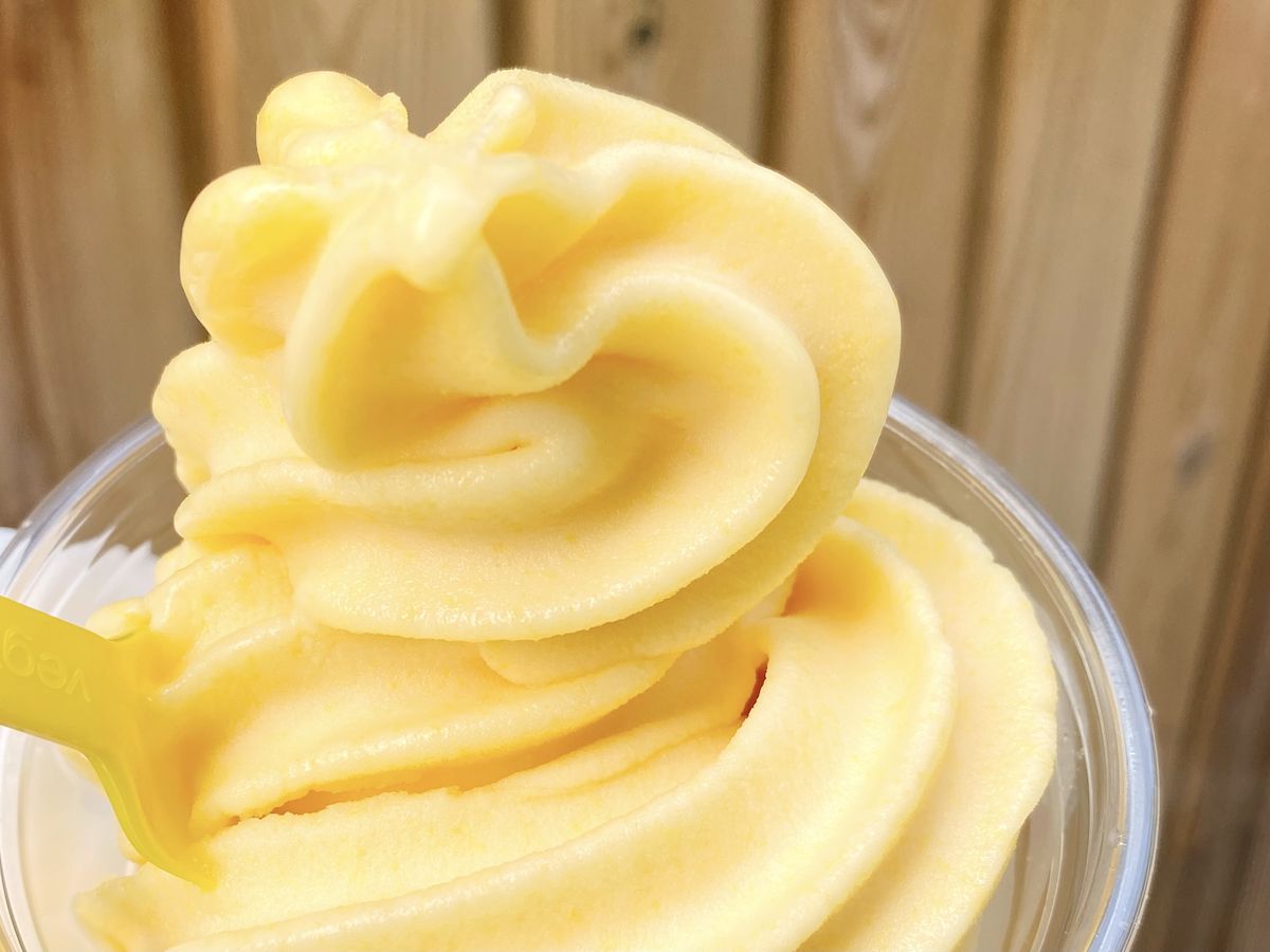 Saffron soft serve in a yellow swirl, in a plastic cup.