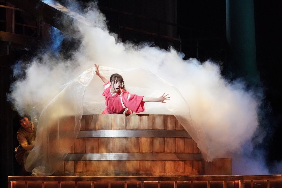 Chihiro stands in a giant bathtub full of smoke in Spirited Away: Live on Stage